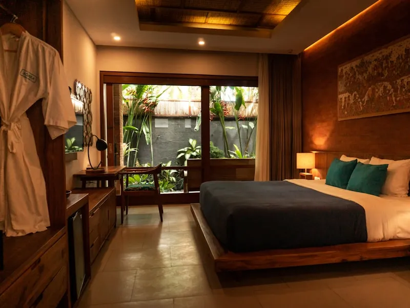 Dark-timber Balinese suite opening onto a planted courtyard in Ubud