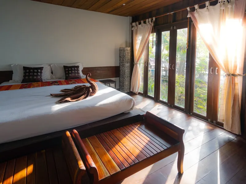 Teak-floored garden villa room with shuttered doors onto tropical greenery